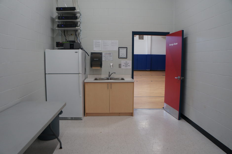 A room with a kitchenette and a door that opens to a gymnasium