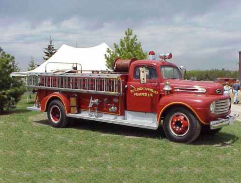 A red 1951 Hickey pumper fire truck on a grassy lawn