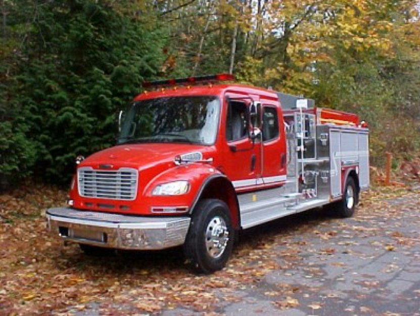 A side view of an American Lafrance (HUB) pumper fire truck on a leafy road 