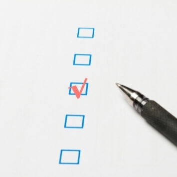 A check marked in the third of 5 blue boxes with a pen laying beside it.